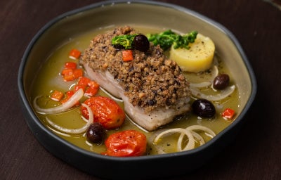 Bacalhau confitado no azeite com legumes, batata, tomates‑cereja e crosta crocante de azeitonas