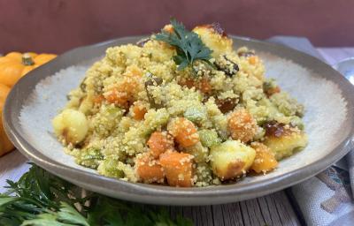 Foto da receita de Cuscuz Marroquino. Observa-se um prato de cerâmica claro redondo contendo a receita finalizada com um ramo de salsa verde. Foto da receita de Cuscuz Marroquino. Observa-se um prato de cerâmica claro redondo contendo a receita finalizada com um ramo de salsa verde.