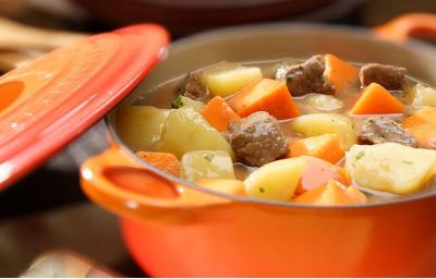 foto tirada de uma panela laranja com pedaços de carne com colorau, batata e abóbora e ao lado a tampa foto tirada de uma panela laranja com pedaços de carne com colorau, batata e abóbora e ao lado a tampa