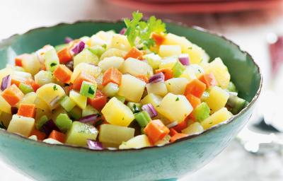 foto tirada de um suporte para servir pratos na cor verde e dentro contém a salada com pedaços de batata-doce, salsão, cenoura e cebola roxa.