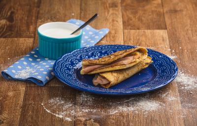 Imagem em tons de marrom e azul claro e escuro. No centro há um prato azul com duas quesadillas recheadas e, ao lado esquerdo, há um tecido azul com bolinhas brancas e, sobre ele, um pote azul com o creme azedo e uma colher. Imagem em tons de marrom e azul claro e escuro. No centro há um prato azul com duas quesadillas recheadas e, ao lado esquerdo, há um tecido azul com bolinhas brancas e, sobre ele, um pote azul com o creme azedo e uma colher.
