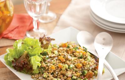 uma mesa contém duas taças de vidro, pratos e um prato quadrado com a salada de sevadinha e duas colheres ao lado.