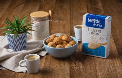 Foto da receita de bolinha crocante de queijo com nestlé aveia disposta em diversas porções dentro de um pote azul claro com um vaso de planta e a embalagem de aveia ao lado