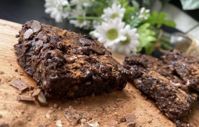 Imagem da receita de Brownie Rápido de Chocolate com Aveia sobre uma mesa e atrás umas flores Imagem da receita de Brownie Rápido de Chocolate com Aveia sobre uma mesa e atrás umas flores