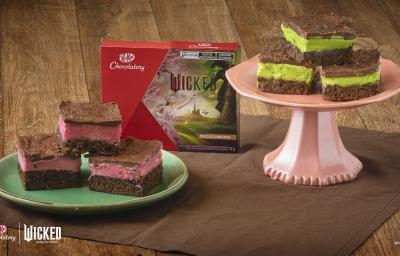 Receita de Brownie Wicked, servidos em pedaços de brownie de chocolate, metade com creme rosa e metade com creme verde, todos cobertos com Chocolate. Alguns em prato verde e outros em um prato rosa alto. No meio há uma caixa de KitKat Wicked.