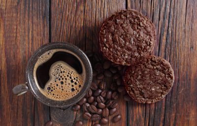 Foto vista de cima da receita de cookies de aveia e café, servidos em uma bancada de madeira, ao lado de uma xícara de café preparada com alguns grãos de café espalhados Foto vista de cima da receita de cookies de aveia e café, servidos em uma bancada de madeira, ao lado de uma xícara de café preparada com alguns grãos de café espalhados