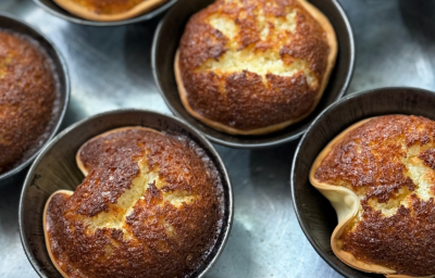 Fotografia mostra as cocadas vistas de cima, dispostas em forminhas de alumínio. A massa de pastel forma cestinhas douradas com o recheio em textura de bolo.