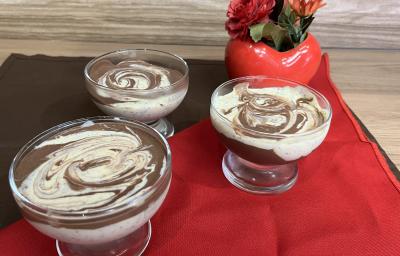 Fotografia de três recipientes com mousse de maracujá com creme de nescau mesclado. Os recipientes estão sobre um pano vermelho e um pano marrom de tom escuro. Fotografia de três recipientes com mousse de maracujá com creme de nescau mesclado. Os recipientes estão sobre um pano vermelho e um pano marrom de tom escuro.