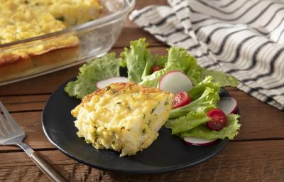 Foto da receita de bolo salgado servida com salada de alface em um prato de porcelana preto sobre uma mesa de madeira com uma espátula prateada ao lado Foto da receita de bolo salgado servida com salada de alface em um prato de porcelana preto sobre uma mesa de madeira com uma espátula prateada ao lado