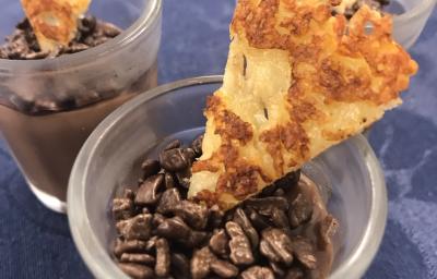 Foto aproximada de um brigadeiro no copinho, decorado com grão de café e um biscoito