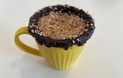 Foto em tons de amarelo da receita de shake de nescau energizante com amendoim servida em uma caneca amarela com cobertura de pasta de nescau e amendoim sobre uma mesa branca Foto em tons de amarelo da receita de shake de nescau energizante com amendoim servida em uma caneca amarela com cobertura de pasta de nescau e amendoim sobre uma mesa branca