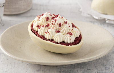 Fotografia de um ovo de páscoa de casca branca, recheado com bolo red velvet e creme branco