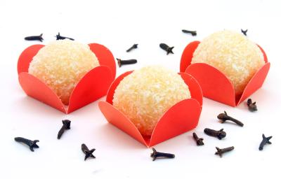 Fotografia de três unidades de beijinho com gelatina dentro de embalagens vermelhas sobre uma mesa branca, com cravos espalhados. Fotografia de três unidades de beijinho com gelatina dentro de embalagens vermelhas sobre uma mesa branca, com cravos espalhados.
