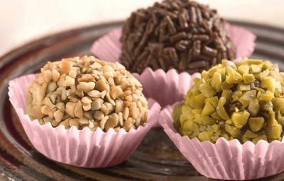 3 brigadeiros em forminhas lilás um com granulado por cima e os outros com castanhas picadas 3 brigadeiros em forminhas lilás um com granulado por cima e os outros com castanhas picadas