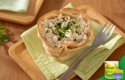 Torta de frango com recheio cremoso servida em massa dourada, finalizada com ervas verdes.