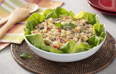 Fotografia em tons de verde em uma bancada de madeira, um pano com listras coloridas, um jogo americano redondo de vime escuro e um recipiente branco redondo fundo com a salada marroquina com vários legumes dentro dela. Fotografia em tons de verde em uma bancada de madeira, um pano com listras coloridas, um jogo americano redondo de vime escuro e um recipiente branco redondo fundo com a salada marroquina com vários legumes dentro dela.