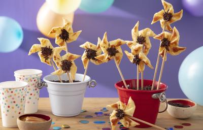 Foto da Receita de Cata-ventos. Observa-se os cata-ventos em latinhas coloridas em uma ambientação colorida e com bexigas.