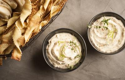 fotografia em tons de cinza, branco e pardo de uma bancada cinza vista de cima. Contém dois potinhos redondos e pretos com uma pasta de creme, e ao lado biscoitinhos para servir junto ao creme. fotografia em tons de cinza, branco e pardo de uma bancada cinza vista de cima. Contém dois potinhos redondos e pretos com uma pasta de creme, e ao lado biscoitinhos para servir junto ao creme.