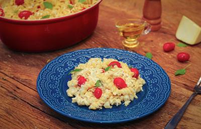 Imagem de um prato azul com macarrão com tomate e queijo feta e ao lado, um pedaço de queijo, tomatinhos e azeite. Imagem de um prato azul com macarrão com tomate e queijo feta e ao lado, um pedaço de queijo, tomatinhos e azeite.