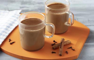 Imagem aproximada da receita Chocolatino Zero Lactose, servido em duas canecas de vidro. A bebida é de um tom marrom escuro e está sobre uma tábua em tom laranja, sobre um bancada decorada com um tecido, alguns paus de canela e cravos Imagem aproximada da receita Chocolatino Zero Lactose, servido em duas canecas de vidro. A bebida é de um tom marrom escuro e está sobre uma tábua em tom laranja, sobre um bancada decorada com um tecido, alguns paus de canela e cravos