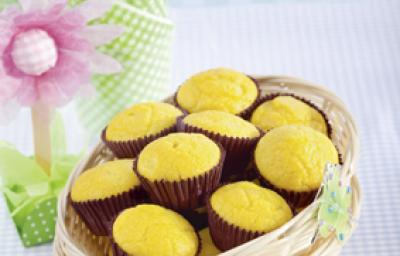 Fotografia em tons de azul, marrom e amarelo, com cestinhas brancas sobrepostas contendo bolinhos em forminhas marrons, sobre toalha quadriculada em branco e azul, com decoração de motivo floral ao lado e fundo em tons de azul. Fotografia em tons de azul, marrom e amarelo, com cestinhas brancas sobrepostas contendo bolinhos em forminhas marrons, sobre toalha quadriculada em branco e azul, com decoração de motivo floral ao lado e fundo em tons de azul.