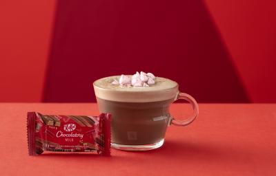 Foto da receita de Chocolate Quente. Observa-se um fundo vermelho com o chocolate quente em uma xícara de vidro transparente. Na frente, um kit kat fechado ao leite. Foto da receita de Chocolate Quente. Observa-se um fundo vermelho com o chocolate quente em uma xícara de vidro transparente. Na frente, um kit kat fechado ao leite.