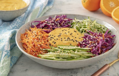 imagem mostra salada arco-íris com cenoura, repolho roxo e pepino, finalizada com mix de gergelim torrado e molho cítrico de Fiber Mais® sabor Laranja.