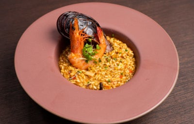 Paella de frutos do mar com camarão, mexilhão e arroz cremoso, finalizada com brotos