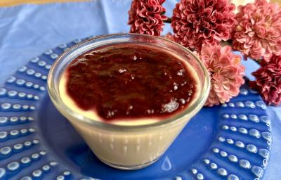 Fotografia em tons de azul e rosa com um pote transparente ao centro. Dentro do pote existe uma receita de flan de mamão coberto com geleia de frutas. Fotografia em tons de azul e rosa com um pote transparente ao centro. Dentro do pote existe uma receita de flan de mamão coberto com geleia de frutas.