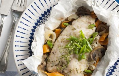 Fotografia em tons de azul em uma mesa de madeira azul com um prato branco fundo com detalhes azuis e o filé de peixe com legumes dentro dele. Fotografia em tons de azul em uma mesa de madeira azul com um prato branco fundo com detalhes azuis e o filé de peixe com legumes dentro dele.