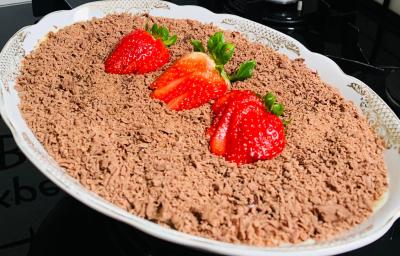 Foto aproximada da receita de bombom de morango na travessa fácil, servido em uma travessa branca de porcelana, decorado com raspas de chocolate ao leite por cima e morangos fatiados Foto aproximada da receita de bombom de morango na travessa fácil, servido em uma travessa branca de porcelana, decorado com raspas de chocolate ao leite por cima e morangos fatiados
