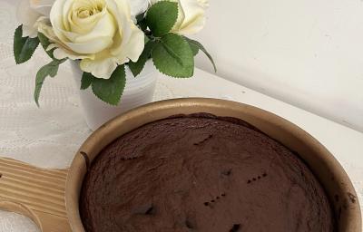 Fotografia de uma forma redonda antianderente com um brownie de chocolate e batata doce. A forma está sobre uma tábua de madeira.