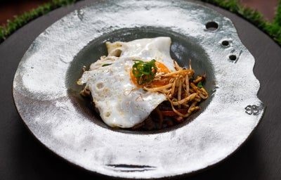 Bibimbap coreano com arroz, legumes salteados, brotos, cebolinha e ovo com gema mole