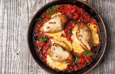 Fotografia de um peito de frango grelhado servido com molho de tomate e queijo