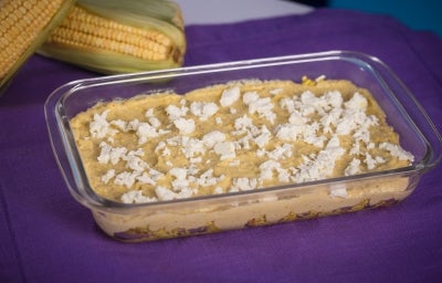 Fotografia em tons amarelo e roxo com uma travessa de vidro ao centro. Na travessa, existe uma receita de Fricassê de frango feita com Ascenda e finalizada com queijo branco. Fotografia em tons amarelo e roxo com uma travessa de vidro ao centro. Na travessa, existe uma receita de Fricassê de frango feita com Ascenda e finalizada com queijo branco.