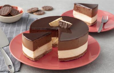 Fotografia em tons de vermelho em uma bancada de madeira cinza, um pano cinza listrado, um prato vermelho redondo raso com a torta mousse de chocolate com recheio de sorvete de creme e cobertura de chocolate. Fotografia em tons de vermelho em uma bancada de madeira cinza, um pano cinza listrado, um prato vermelho redondo raso com a torta mousse de chocolate com recheio de sorvete de creme e cobertura de chocolate.