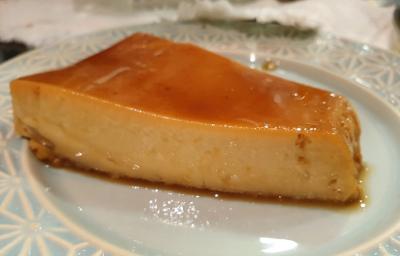 Foto de uma fatia da receita de pudim de doce de leite com calda de café servida sobre um prato de porcelana azul claro com adornos em branco Foto de uma fatia da receita de pudim de doce de leite com calda de café servida sobre um prato de porcelana azul claro com adornos em branco