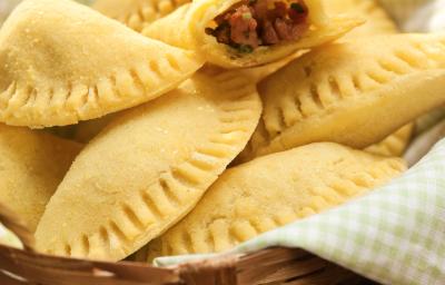 em um cesto com um pano em tons de verde claro contém diversos pasteis e dois abertos recheados com linguiça em um cesto com um pano em tons de verde claro contém diversos pasteis e dois abertos recheados com linguiça