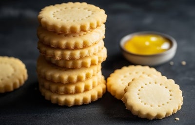 Em cima de uma mesa, biscoitos dourados e redondos com furos no meio. Em cima de uma mesa, biscoitos dourados e redondos com furos no meio.