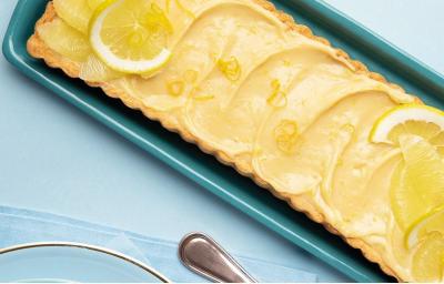 fotografia e tons de azul e amarelo tirada de cima de uma bandeja azul com a torta e rodelas de limão por cima fotografia e tons de azul e amarelo tirada de cima de uma bandeja azul com a torta e rodelas de limão por cima