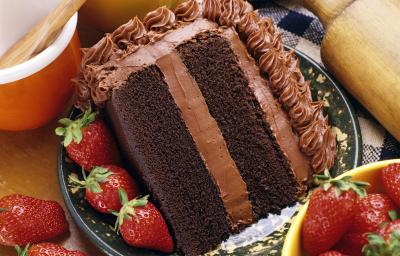 Fotografia de uma fatia de bolo com massa e recheio de chocolate, morangos por toda a parte em um prato desenhado de cor escura, apoiado em uma toalha de mesa azul e branca, quadriculada. Ao lado do bolo, dois potes e um rolo de massa. Fotografia de uma fatia de bolo com massa e recheio de chocolate, morangos por toda a parte em um prato desenhado de cor escura, apoiado em uma toalha de mesa azul e branca, quadriculada. Ao lado do bolo, dois potes e um rolo de massa.