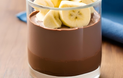 Foto da Receita de Mousse Chocolate com Banana. Observa-se um copo com o mousse dentro e bananas decorando o topo. Imagem ilustrativa gerada por inteligência artificial.