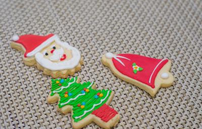 Fotografia de três biscoitos de gengibre em formatos diferentes com decorações natalinas, sobre uma mesa de tom claro. Fotografia de três biscoitos de gengibre em formatos diferentes com decorações natalinas, sobre uma mesa de tom claro.