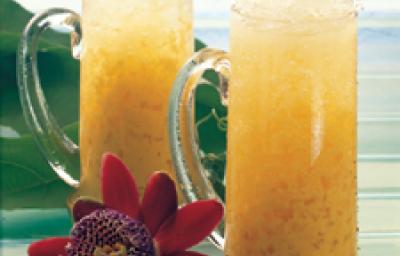 fotografia tirada de dois copos transparentes com o refresco de maracujá com gelo picado por cima
