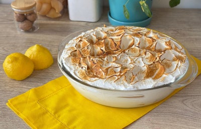 Fotografia mostra um recipiente oval e transparente com um creme branco. Na parte superior ao creme, um merengue maçaricado.