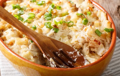 Close de bacalhau com natas gratinado, com pedaços de bacalhau, batata e cebolinha em refratário.