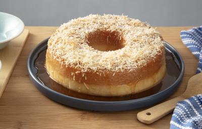 Foto da receita de pudim de tapioca com calda de coco queimado servido em uma porção grande sobre um prato azul escuro em cima de uma mesa de madeira com um paninho azul listrado Foto da receita de pudim de tapioca com calda de coco queimado servido em uma porção grande sobre um prato azul escuro em cima de uma mesa de madeira com um paninho azul listrado