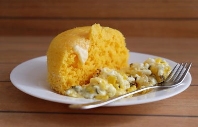 imagem mostra um cuscuz de milho amarelo com um ovo frito por cima
