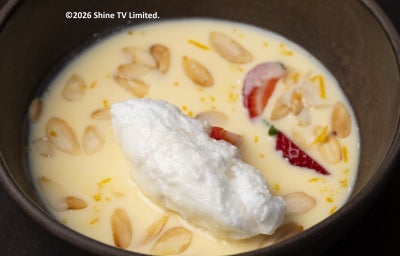 Ovos nevados sobre creme inglês com amêndoas torradas e morango fatiado