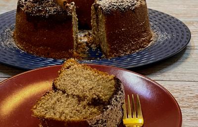 Foto da receita de Bolo com Farofa de Canela. Observa-se um prato de sobremesa com uma fatia do bolo e um garfinho e, atrás, o bolo maior em um prato grande azul. Foto da receita de Bolo com Farofa de Canela. Observa-se um prato de sobremesa com uma fatia do bolo e um garfinho e, atrás, o bolo maior em um prato grande azul.